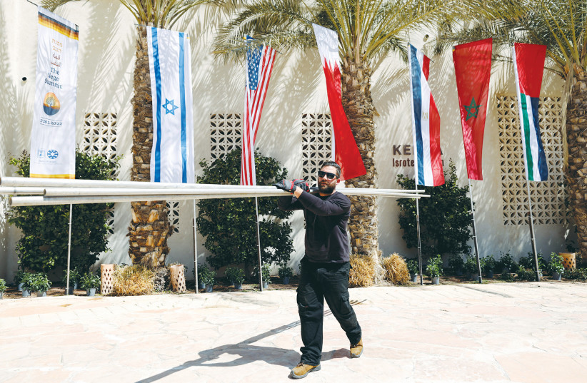  A WORKER carries flagpoles in preparation for the Negev Summit in Sde Boker on March 27. (photo credit: AMIR COHEN/REUTERS)