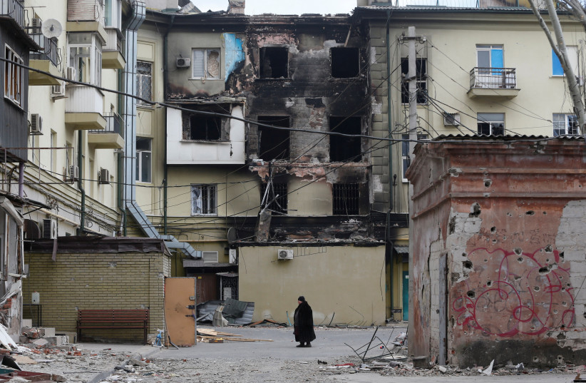  A woman stands near a building damaged during Ukraine-Russia conflict in the besieged southern port city of Mariupol, Ukraine April 3, 2022. (photo credit: REUTERS/ALEXANDER ERMOCHENKO)