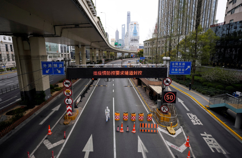  A worker in a protective suit walks at an entrance to a tunnel leading to the Pudong area across the Huangpu river, after restrictions on highway traffic amid the lockdown to contain the spread of the coronavirus disease (COVID-19) in Shanghai, China March 28, 2022. (credit: ALY SONG/REUTERS)