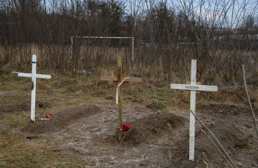  Graves with bodies of civilians, who according to local residents were killed by Russian soldiers, are seen, as Russia's attack on Ukraine continues, in Bucha, in Kyiv region, Ukraine April 4, 2022. The inscription on a cross reads: "Unknown".  (photo credit: REUTERS/VLADYSLAV MUSIIENKO)