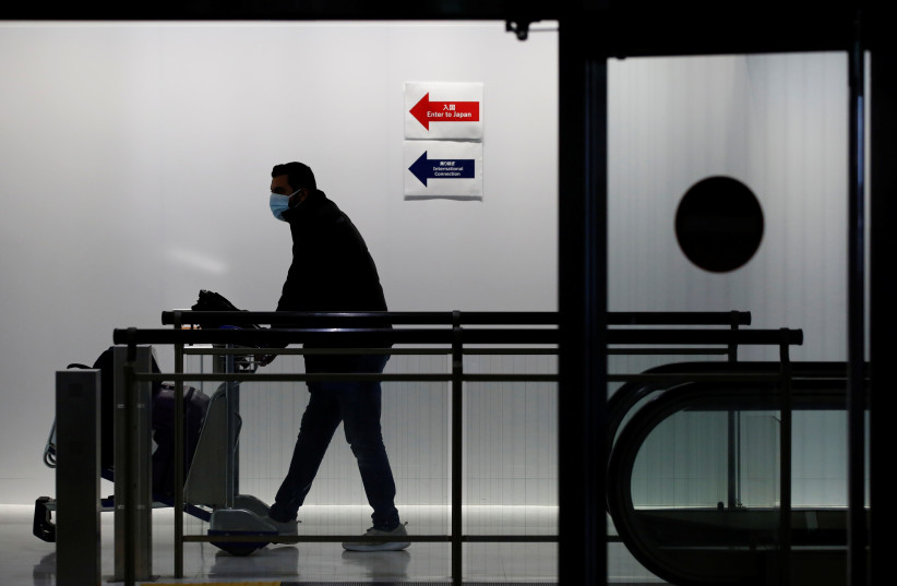  A passenger wearing a protective mask makes his way next to an arrival gate of Narita international airport on the first day of closed borders to prevent the spread of the new coronavirus Omicron variant amid the coronavirus disease (COVID-19) pandemic in Narita, east of Tokyo, Japan, November 30,  (credit: REUTERS/KIM KYUNG-HOON)