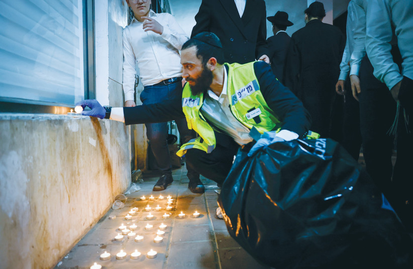  A MEMBER of the ZAKA organization lights candles at the scene of the terror attack in Bnei Brak last week in memory of those killed.  (photo credit: OLIVIER FITOUSSI/FLASH90)
