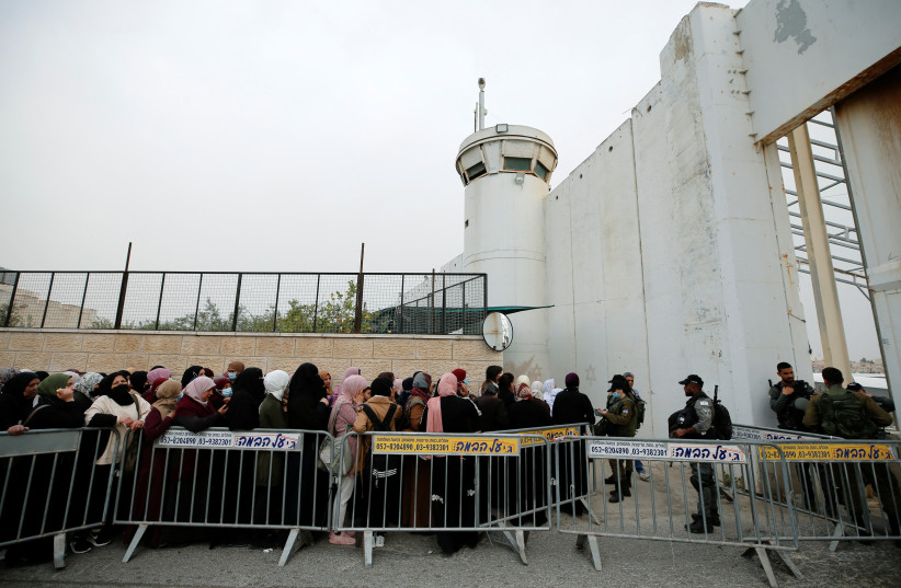  Palestinians make their way through an Israeli checkpoint to attend the first Friday prayers of Ramadan in Jerusalem's al-Aqsa mosque, in Bethlehem in the West Bank, April 8, 2022. (credit: MUSSA ISSA QAWASMA/REUTERS)