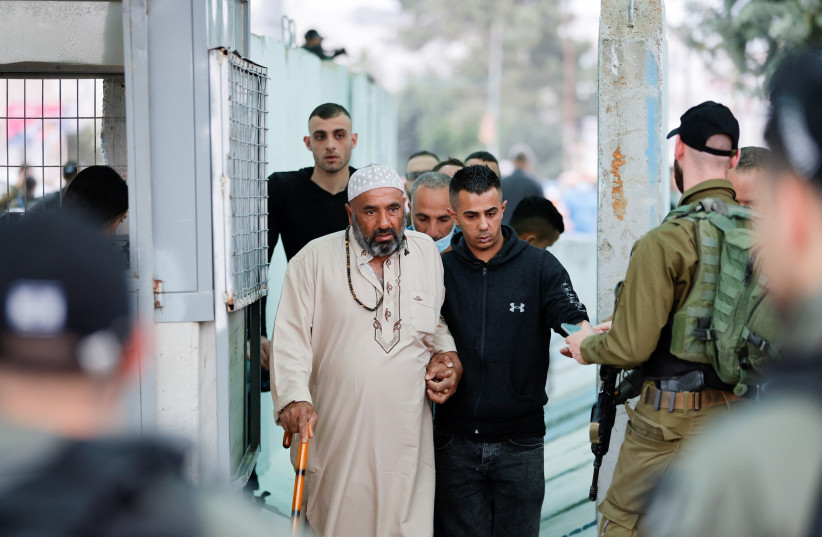  Palestinians make their way through an Israeli checkpoint to attend the first Friday prayers of Ramadan in Jerusalem's al-Aqsa mosque, in Bethlehem in the West Bank, April 8, 2022. (photo credit: MUSSA ISSA QAWASMA/REUTERS)