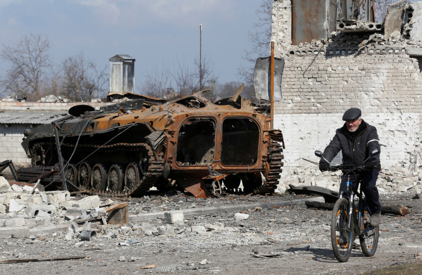   A local resident rides a bicycle past a charred armoured vehicle during Ukraine-Russia conflict in the separatist-controlled town of Volnovakha in the Donetsk region, Ukraine March 15, 2022 (photo credit: REUTERS/ALEXANDER ERMOCHENKO)