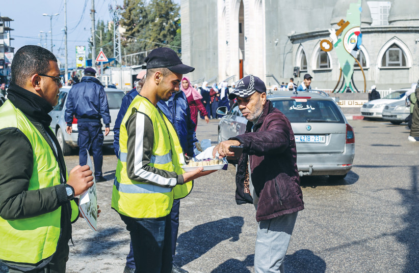  A PALESTINIAN hands out sweets in the Gaza Strip after a terrorist attack in Jerusalem in November in which one person was killed. (photo credit: ATIA MOHAMMED/FLASH90)