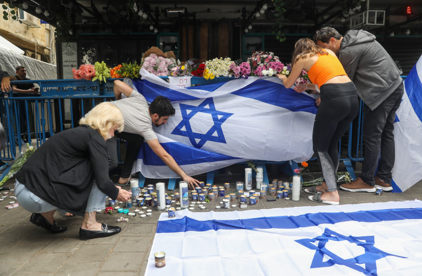 Des Israéliens allument des bougies sur les lieux d'un attentat terroriste dans la rue Dizengoff, au centre de Tel-Aviv. 2 personnes ont été tuées et plusieurs autres blessées lors de l'attaque terroriste de la nuit dernière, le 8 avril 2022 (crédit : NOAM REVKIN FENTON/FLASH90)