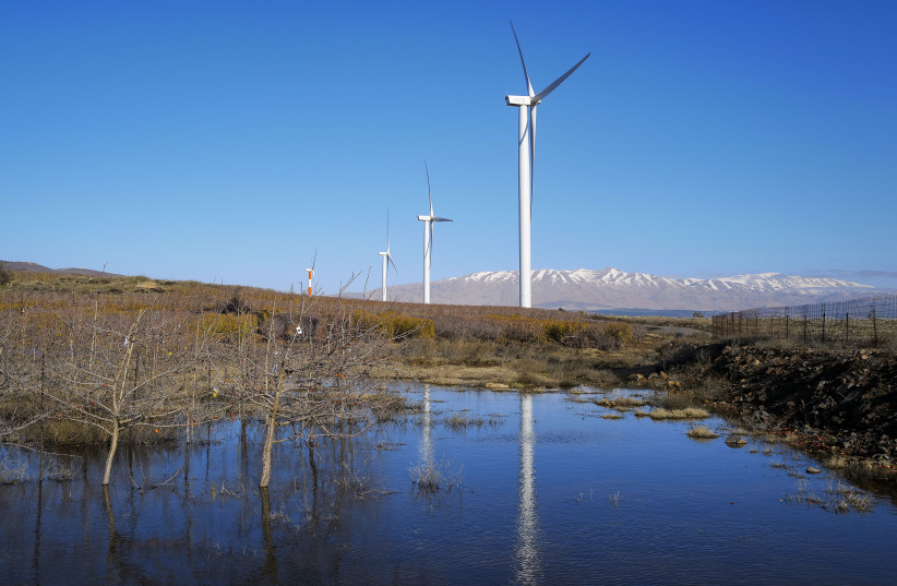 Renewable energy wind turbines as seen next to the snowy peaks of Mount Hermon on January 3, 2021. Northern Golan Heights. (credit: MICHAEL GILADI/FLASH90)