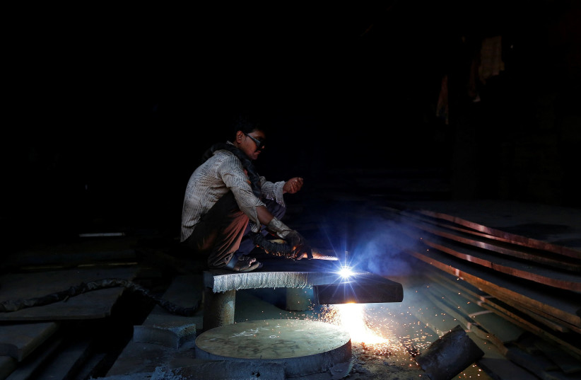  A worker welds metal at a scrapyard at an industrial area in Mumbai February 12, 2014. (credit: Mansi Thapliyal/Reuters)