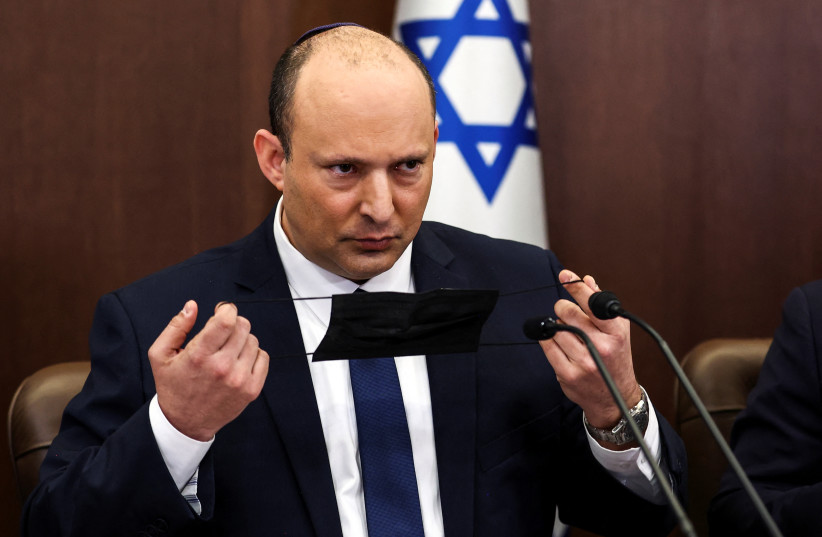  Israeli Prime Minister Naftali Bennett handles his mask at a cabinet meeting at the Prime Minister's office in Jerusalem April 10, 2022.  (credit: RONEN ZVULUN/REUTERS)