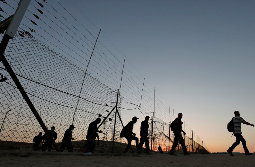  Palestinian laborers cross through an opening in the security fence between the West Bank and sovereign Israel, as they head to work in Israel, near Hebron August 11, 2020. (photo credit: REUTERS/MUSSA QAWASMA)