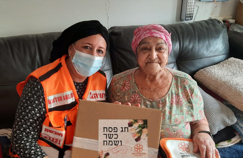  A woman in Beit Shemesh receives a package of matza and grape juice from a United Hatzalah volunteer with the Ten Kavod project ahead of Passover (photo credit: UNITED HATZALAH‏)