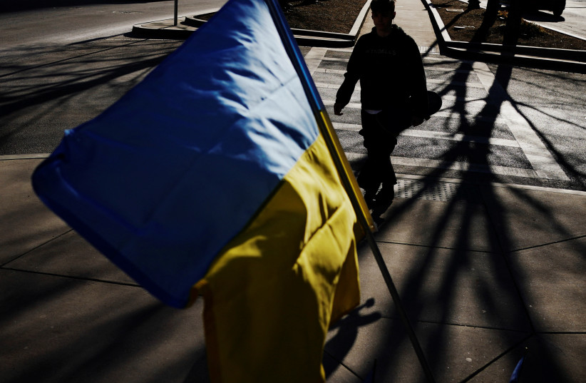  A pedestrian passes an Ukrainian flag, part of a display of over 500 of the flags in support of the country, following Russia's invasion of Ukraine, in downtown Boston, Massachusetts, US, March 14, 2022.  (photo credit: REUTERS/BRIAN SNYDER)