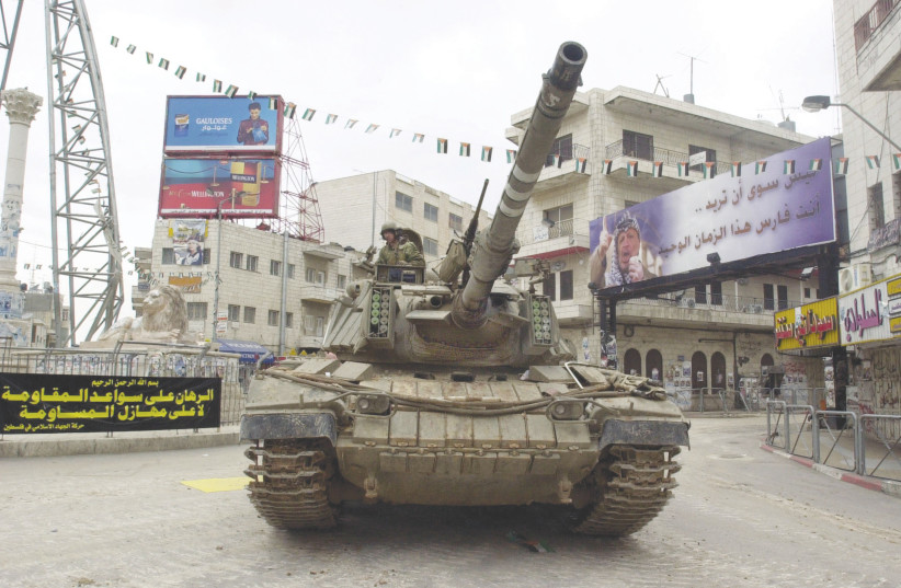  AN ISRAELI tank patrols the deserted central square of Ramallah on March 31, 2002, two days after Israel launched Operation Defensive Shield.  (photo credit: Scott Nelson/Getty Images)