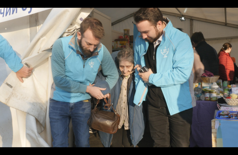  Alex Weisler (second from left) escorts refugee Galina Chornobyl from an aid tent at the Siret border in Romania to a car that transported her family to Bucharest.  (photo credit: JDC)