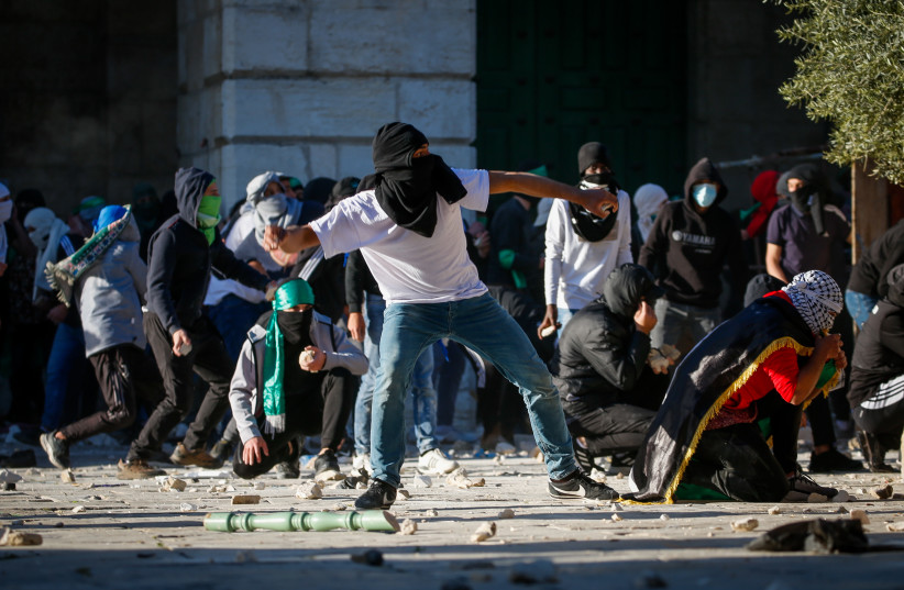  Palestinian protesters hurl stones towards Israeli security forces during clashes on the holy month of Ramadan at the Al-Aqsa mosque compound in Jerusalem's Old City on April 15, 2022.  (photo credit: JAMAL AWAD/FLASH90)