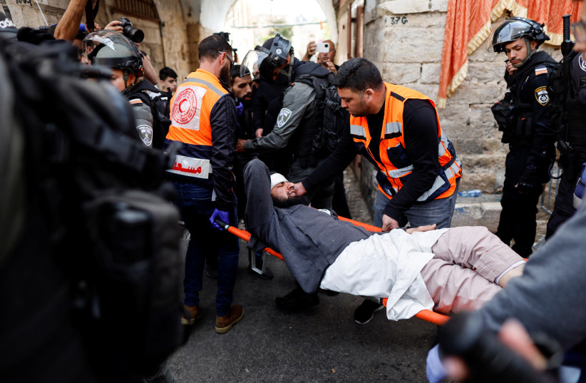  Rescue personnel evacuate an injured man outside the compound that houses Al-Aqsa Mosque, known to Muslims as Noble Sanctuary and to Jews as Temple Mount, in Jerusalem's Old City April 17, 2022.  (credit: AMMAR AWAD/REUTERS)