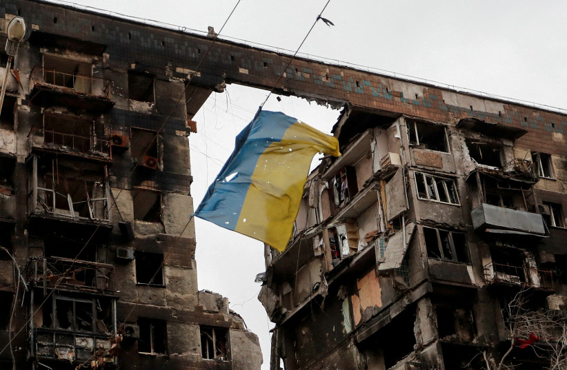  A view shows a torn flag of Ukraine hung on a wire in front an apartment building destroyed during Ukraine-Russia conflict in the southern port city of Mariupol, Ukraine April 14, 2022.  (photo credit: REUTERS/ALEXANDER ERMOCHENKO)