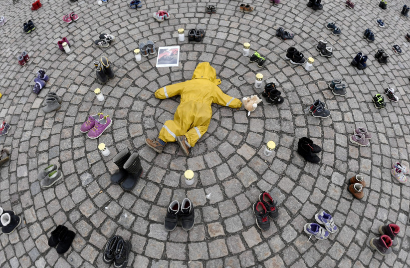  Child's overalls, shoes and boots are placed beside candles during a demonstration organised by the Ukrainian Association in Finland to honour the memory of the children killed amid the Russian invasion in the Ukrainian city of Mariupol, in Helsinki, Finland, April 10, 2022. (photo credit: Lehtikuva/Jussi Nukari via REUTERS)