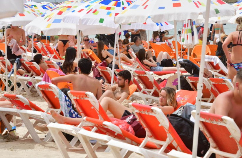  Israelis are seen visiting the beach in Tel Aviv amid a heatwave on the Passover holiday, on April 18, 2022. (photo credit: AVSHALOM SASSONI/MAARIV)