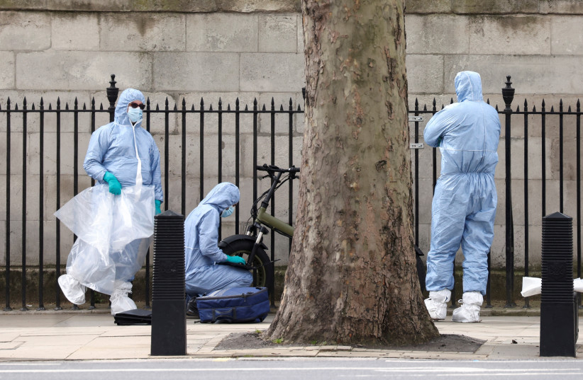 Police forensic officials work at a cordoned-off area on Whitehall in Westminster after the road was closed by police following an incident involving the arrest of a man near Downing Street, in London, Britain, April 18, 2022.  (photo credit: REUTERS/HENRY NICHOLLS)
