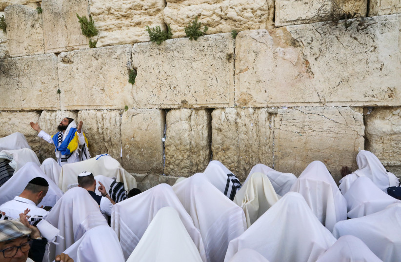  A worshiper draped in Ukraine's flag during priestly blessing at the Western Wall in Jerusalem during Passover, April 18, 2022 (credit: MARC ISRAEL SELLEM)