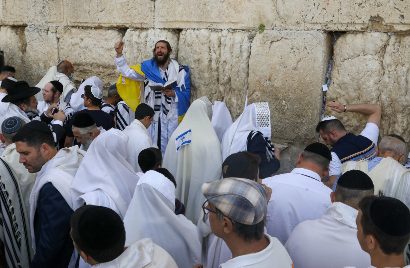  A worshiper draped in Ukraine's flag during priestly blessing at the Western Wall in Jerusalem during Passover, April 18, 2022 (credit: MARC ISRAEL SELLEM)