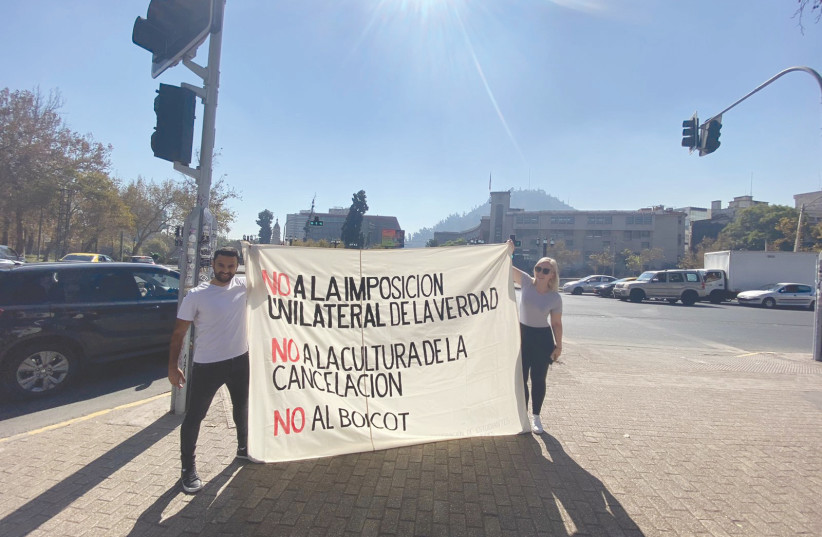 EMILY SCHRADER and Yoseph Haddad hold a sign outside Universidad de Chile, protesting boycotts and cancel culture. (photo credit: Vanessa Hites)