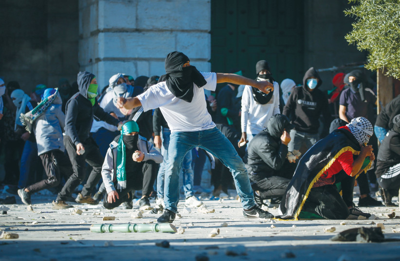  PALESTINIAN PROTESTERS hurl stones toward Israeli security forces during clashes at al-Aqsa Mosque last Friday. (photo credit: JAMAL AWAD/FLASH90)