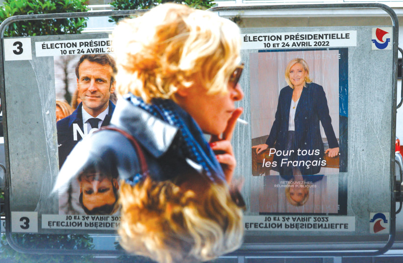  A WOMAN walks past official campaign posters of French presidential election runoff candidates Marine Le Pen and incumbent, Emmanuel Macron, in Paris on Tuesday.  (photo credit: GONZALO FUENTES / REUTERS)
