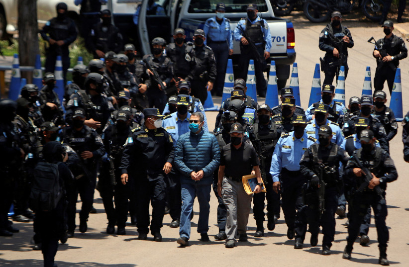  Honduras former President Juan Orlando Hernandez is escorted by members of the National Police to his extradition to the United States, to face a trial on drug trafficking and arms possession charges, at a police base in Tegucigalpa, Honduras April 21, 2022. (photo credit: REUTERS/JONATHAN LAZO)