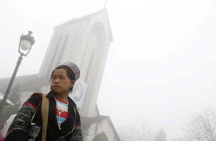  A handicraft vendor waits for customers on a foggy day in front of a Catholic church after Sunday Mass, in Vietnam's northern resort town of Sapa (photo credit: KHAM / REUTERS)