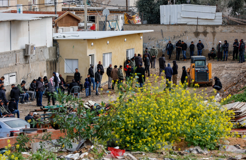 Des hommes bédouins devant la scène où un suspect armé a été tué après avoir tiré sur les forces spéciales de la police qui opéraient à Rahat, dans le sud d'Israël, le 15 mars 2022 (crédit : FLASH90)