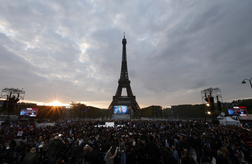  Supporters of French President Emmanuel Macron, candidate for his re-election, react after the results in the second round vote of the 2022 French presidential election, near Eiffel Tower, at the Champs de Mars in Paris, France April 24, 2022. (credit: REUTERS/BENOIT TESSIER)