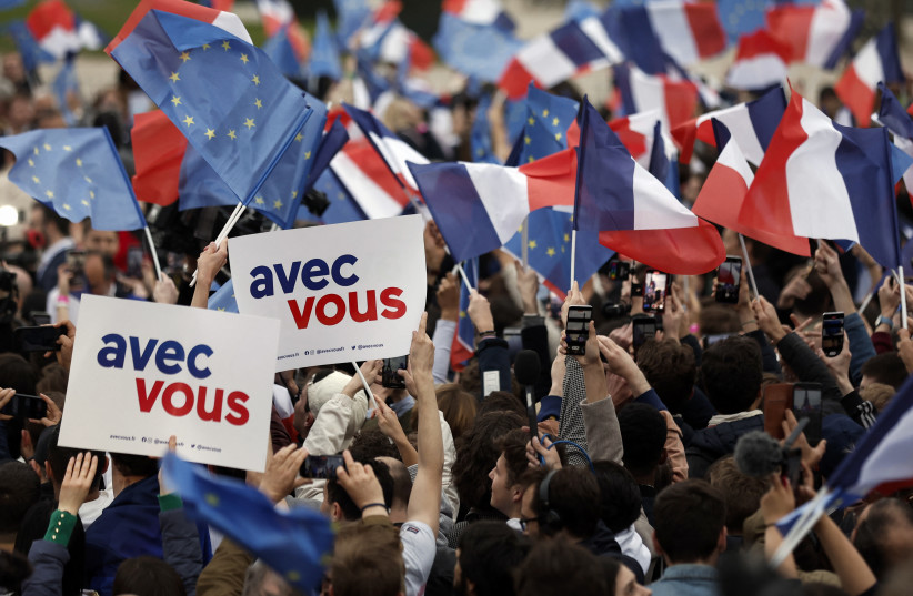  Supporters of French President Emmanuel Macron, candidate for his re-election, wave French and European Union flags as they react after early results in the second round of the 2022 French presidential election, at the Champs de Mars in Paris, France April 24, 2022 (photo credit: REUTERS/BENOIT TESSIER)
