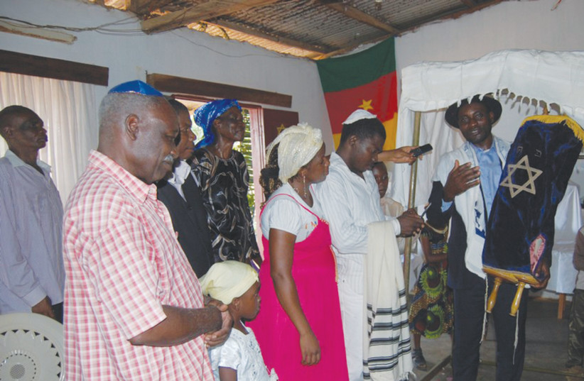 Serge Etele, leader of the Beit Yeshourun Community from Cameroon, holds a Torah Scroll. (photo credit: SERGE ETELE)