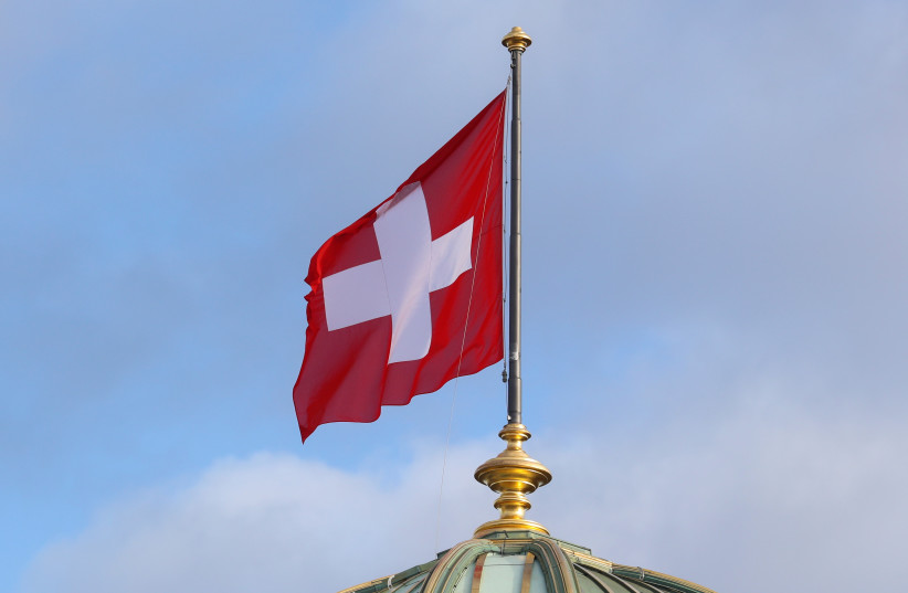 The flag of Switzerland flies on the dome of the Parliament Building (Bundeshaus), as the spread of the coronavirus disease (COVID-19) continues, in Bern, Switzerland, October 28, 2020. (photo credit: REUTERS/ARND WIEGMANN)