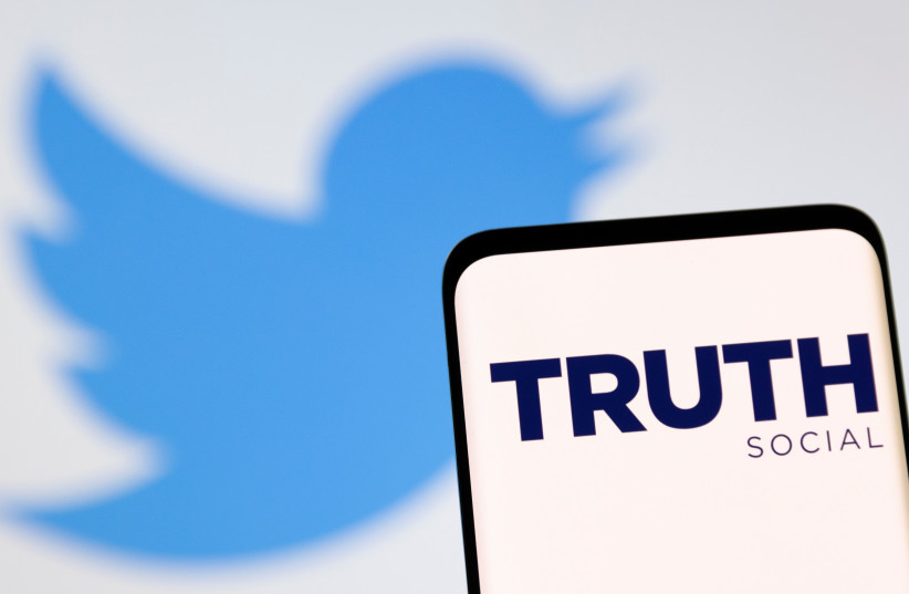 The Truth social network logo is seen on a smartphone in front of display of the Twitter logo in this picture illustration taken February 21, 2022.  (credit: REUTERS/DADO RUVIC/ILLUSTRATION)