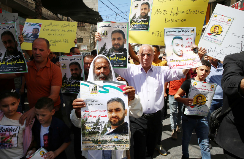 Palestinians hold the pictures Palestinian prisonners detained in Israeli prison starting a  hunger strike against the administrative detention in  the  village Dura, on September 17, 2021. (credit: WISAM HASHLAMOUN/FLASH90)