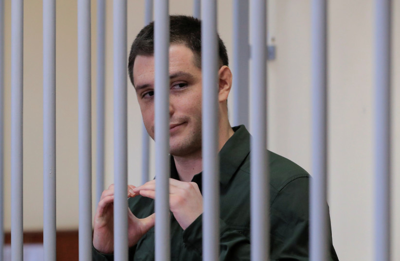  US ex-Marine Trevor Reed, who was detained in 2019 and accused of assaulting police officers, gestures inside a defendants' cage during a court hearing in Moscow, Russia March 11, 2020. (photo credit: REUTERS/TATYANA MAKEYEVA)