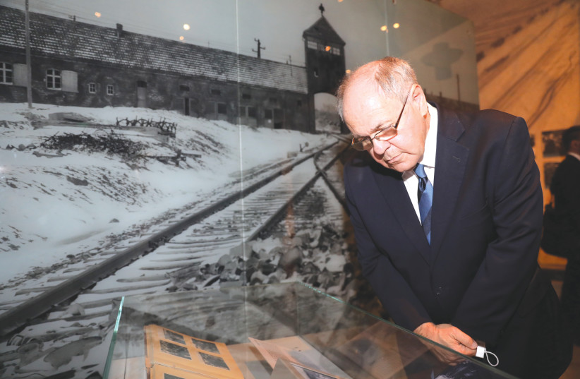 THE WRITER views the Auschwitz Album on display in the Yad Vashem Holocaust History Museum. (photo credit: Noam Rivkin Fenton/Yad Vashem)