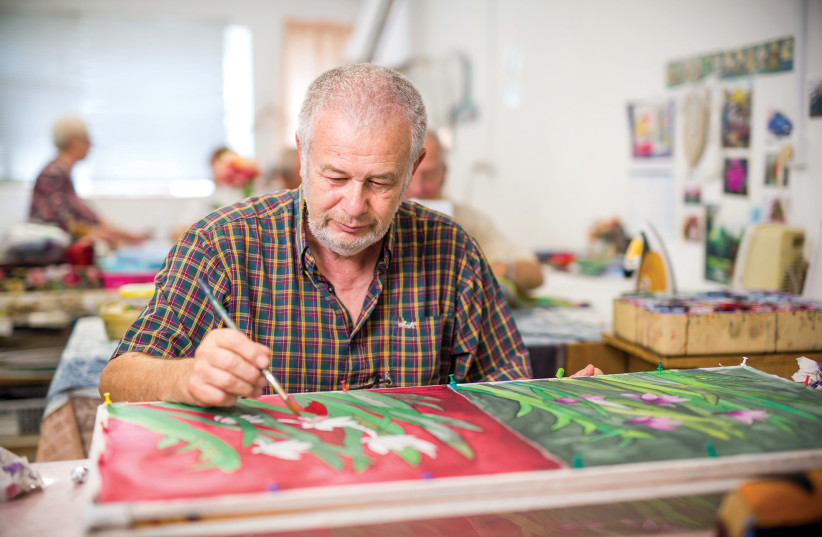  A SILK-SCREEN print workshop artisan applies his skills and professional experience to an alluring floral creation. (credit: Courtesy Yad Lakashish)