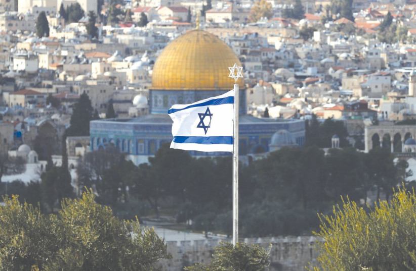  AN ISRAELI flag with a Magen David on top of it appears in the foreground of the Dome of the Rock in Jerusalem’s Old City. (photo credit: AMMAR AWAD/REUTERS)