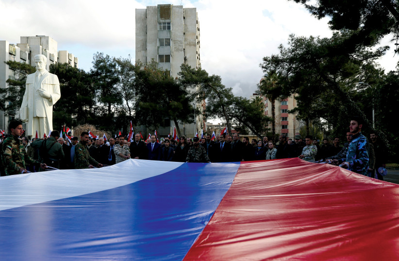  SYRIAN UNIVERSITY students in Damascus hold a giant Russian flag at a pro-Russia rally following the invasion of Ukraine. (credit: YAMAM AL SHAAR/REUTERS)