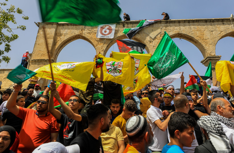 Palestinians wave flags and shout slogans as Muslim worshipers attend the last first Friday prayers of the holy month of Ramadan, at the Al Aqsa Mosque Compound in Jerusalem's Old City, Friday, April 29, 2022. (photo credit: JAMAL AWAD/FLASH90)