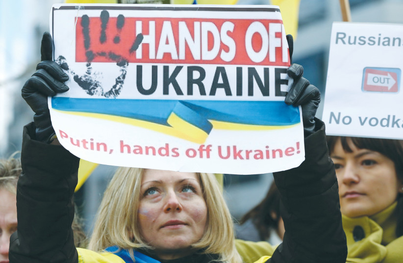  PEOPLE GATHER outside a European Union emergency foreign ministers meeting in Brussels in 2014, to protest against Russian troops in Ukraine. We need to internalize that this is not Russia’s first seizure of territory – remember Crimea in 2014.  (photo credit: YVES HERMAN/REUTERS)