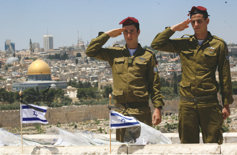  PARATROOPERS SALUTE after placing flags on the graves of fallen soldiers, during preparations for Remembrance Day ceremonies on the Mount of Olives. (credit: NATI SHOHAT/FLASH90)