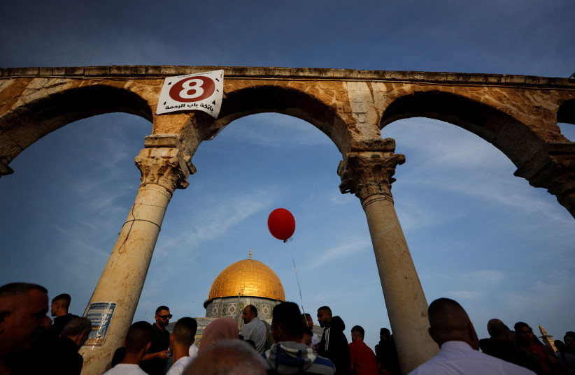  Palestinians hang a giant banner during Eid al-Fitr prayers which marks the end of the holy fasting month of Ramadan, on the compound known to Muslims as Noble Sanctuary and to Jews as Temple Mount in Jerusalem's Old City May 2, 2022. (photo credit: REUTERS/AMMAR AWAD)