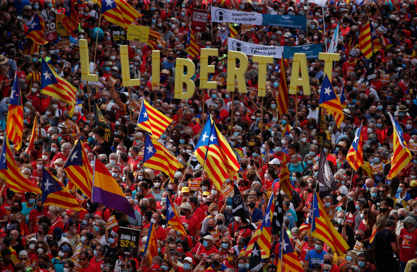  People hold up Estelada flags (Catalan separatist flag) during Catalonia's national day, 'La Diada', in Barcelona, Spain, September 11, 2021. The banner reads ''freedom''. (credit: ALBERT GEA/ REUTERS)