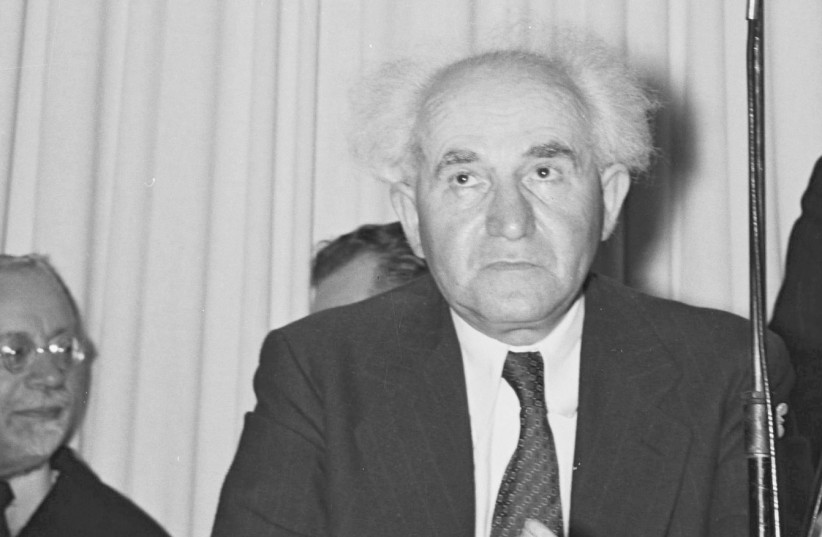 David Ben-Gurion sits under a portrait of Theodor Herzl, before the reading of Israel’s Declaration of Independence in Tel Aviv on May 14, 1948.  (photo credit: FRANK SCHERSCHEL/GPO/REUTERS)